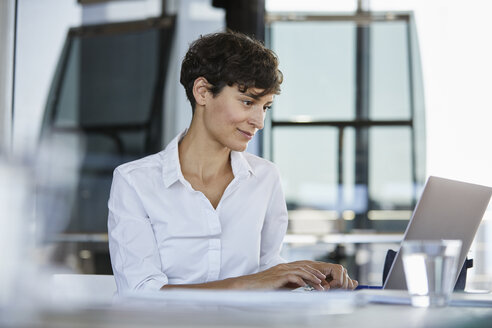 Geschäftsfrau sitzt am Schreibtisch im Büro und benutzt einen Laptop - RBF06852
