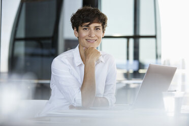 Porträt einer selbstbewussten Geschäftsfrau, die mit einem Laptop am Schreibtisch sitzt - RBF06854