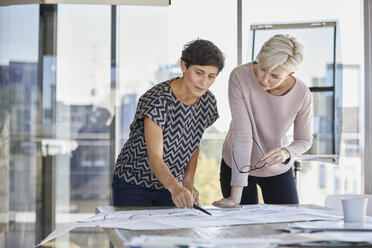 Two businesswomen discussing floor plan on desk in office - RBF06882