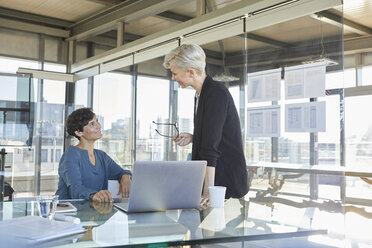 Two smiling businesswomen discussing at desk in office - RBF06896