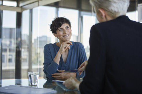 Two businesswomen talking at desk in office - RBF06899