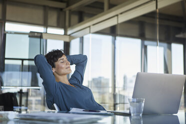 Businesswoman sitting at desk in office with closed eyes - RBF06912