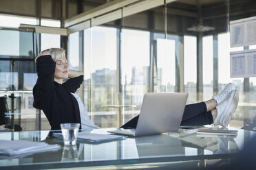 Businesswoman sitting at desk in office with closed eyes - RBF06917