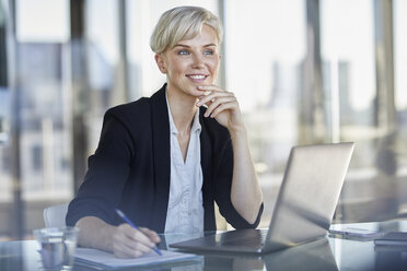 Porträt einer selbstbewussten Geschäftsfrau, die mit einem Laptop am Schreibtisch sitzt - RBF06920