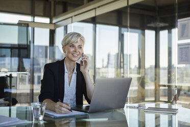 Smiling businesswoman working at desk in office - RBF06924