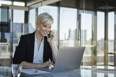 Smiling businesswoman working at desk in office - RBF06925