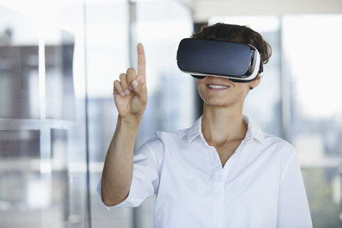 Geschäftsfrau mit VR-Brille im Büro hebt den Finger - RBF06939