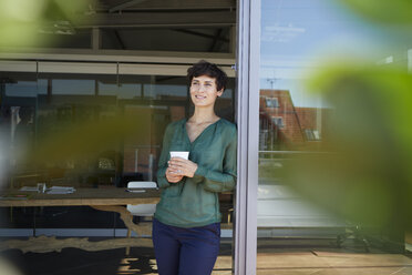 Lächelnde Frau, die am Fenster steht und eine Kaffeepause macht - RBF06942