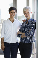 Porträt von zwei lächelnden Geschäftsfrauen am Fenster im Büro - RBF06952