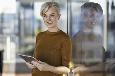 Portrait of smiling businesswoman with tablet at the window - RBF06965