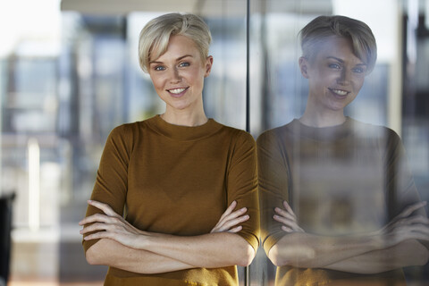 Portrait of smiling woman leaning against window stock photo