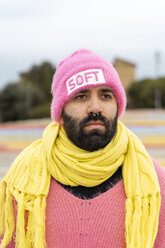 Porträt eines bärtigen Schwulen mit Nasenpiercing, der eine rosafarbene Kappe mit dem Wort 