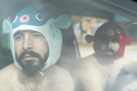 Porträt eines schwulen Paares in einem Auto mit Tierhüten, lizenzfreies Stockfoto