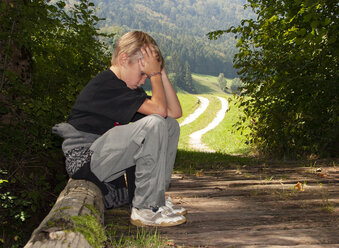 Trauriger Junge sitzt auf einer Holzbrücke - WWF04588