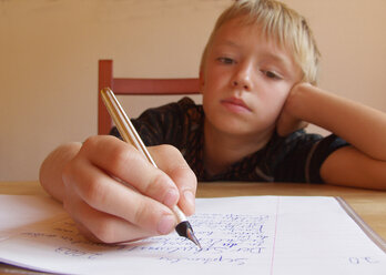 Boy doing his homework, writing in exercise book - WWF04589