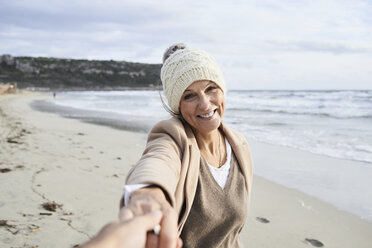 Spain, Menorca, portrait of happy senior woman holding hand on the beach in winter - IGGF00700