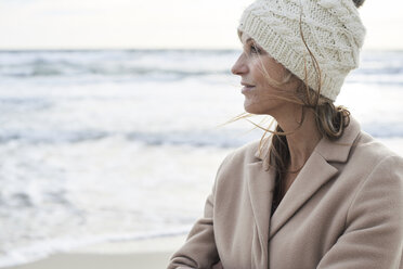 Spain, Menorca, profile of senior woman wearing wooly hat on the beach in winter - IGGF00707