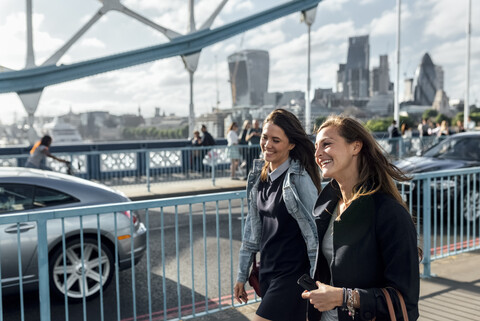 UK, London, zwei glückliche Frauen gehen auf der Tower Bridge spazieren, lizenzfreies Stockfoto