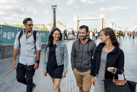 UK, London, glückliche Freunde beim Spaziergang in der Nähe der Tower Bridge, lizenzfreies Stockfoto