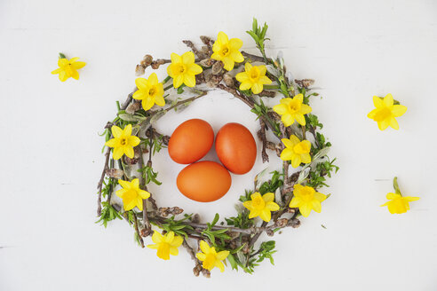 Selbstgemachter Osterkranz und orange gefärbte Eier auf weißem Grund - GWF05749