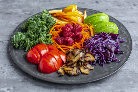 Grünkohl-Avocado-Salat mit Rotkohl, Tomate, gebratenem Champignon, Karotte, Apfel und Himbeere, lizenzfreies Stockfoto