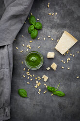 Glass of homemade pesto Genovese, pine nuts, basil leaves and parmesan on grey ground - LVF07616