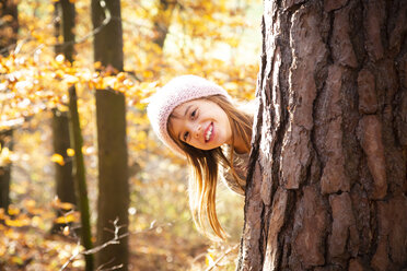 Young girl behind tree in autumn - LVF07630