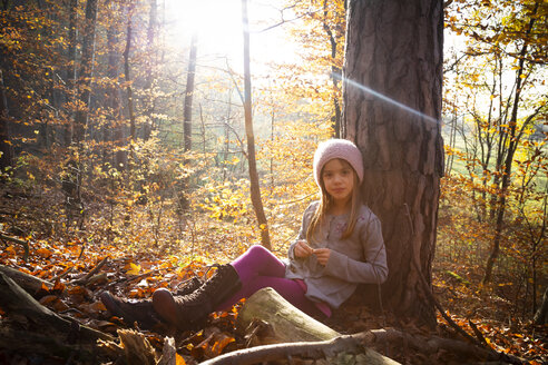 Junges Mädchen sitzt auf einem Baum im Herbst - LVF07632