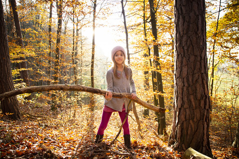 Junges Mädchen hält Zweig im Herbstwald, lizenzfreies Stockfoto