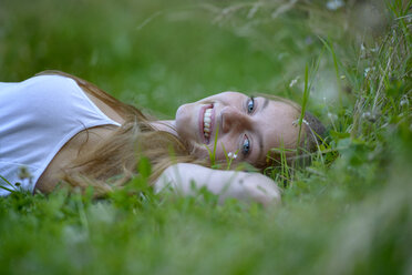 Portrait of happy teenage girl relaxing on a meadow in summer - LBF02314