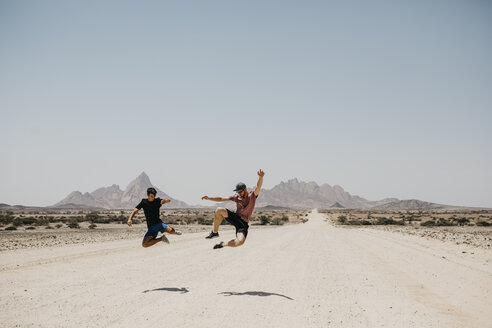 Namibia, zwei Freunde springen auf der Straße zur Spitzkoppe - LHPF00341