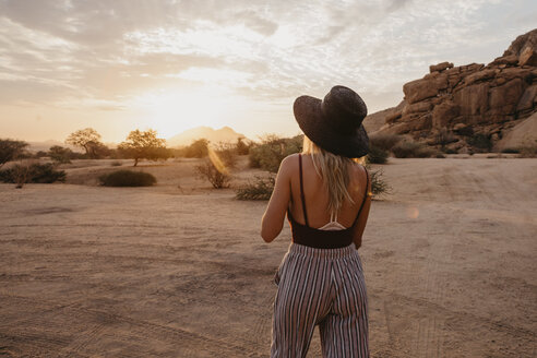 Namibia, Spitzkoppe, Rückansicht einer Frau mit Hut bei Sonnenuntergang - LHPF00362