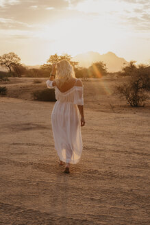 Namibia, Spitzkoppe, Rückansicht einer Frau bei Sonnenuntergang in der Wüstenlandschaft - LHPF00365