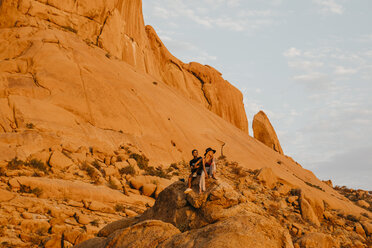 Namibia, Spitzkoppe, Paar sitzt bei Sonnenuntergang auf einem Felsen - LHPF00369