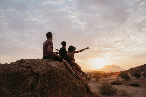 Namibia, Spitzkoppe, Freunde sitzen auf einem Felsen und beobachten den Sonnenuntergang - LHPF00370