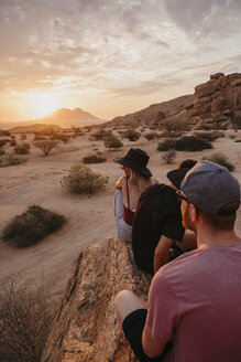 Namibia, Spitzkoppe, Freunde sitzen auf einem Felsen und beobachten den Sonnenuntergang - LHPF00372