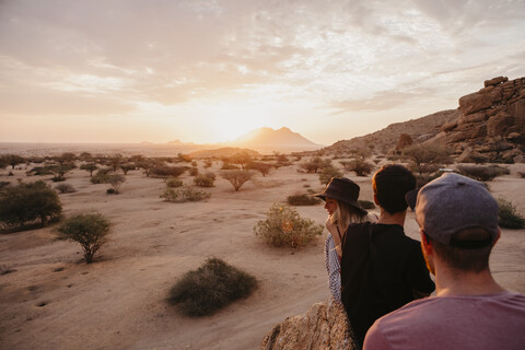 Namibia, Spitzkoppe, friends sitting on a rock watching the sunset stock photo