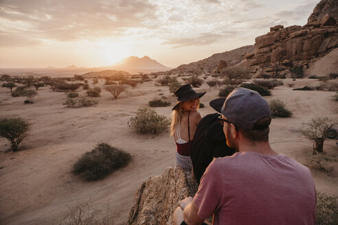 Namibia, Spitzkoppe, Freunde sitzen bei Sonnenuntergang auf einem Felsen - LHPF00374