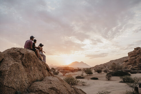 Namibia, Spitzkoppe, Freunde sitzen auf einem Felsen und beobachten den Sonnenuntergang - LHPF00378