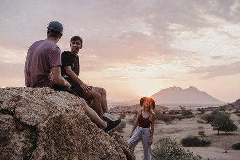 Namibia, Spitzkoppe, Freunde sitzen bei Sonnenuntergang auf einem Felsen - LHPF00380