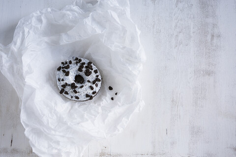 Krapfen mit weißem Zuckerguss und dunklen Schokoladensplittern auf weißem Seidenpapier, lizenzfreies Stockfoto