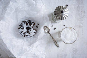 Gebissener Krapfen mit weißer Glasur und dunklen Schokoladensplittern, Mokkakanne, Teelöffel und Glas Cappuccino - OJF00320