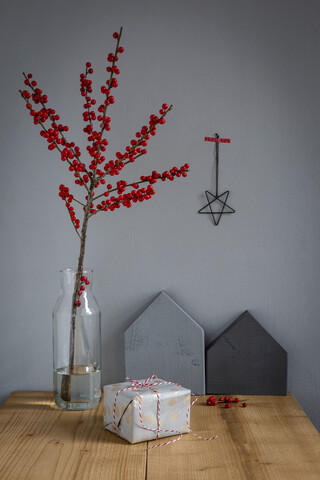 Eingepacktes Geschenk, Dekoration und Stechpalmenzweig in Vase, lizenzfreies Stockfoto