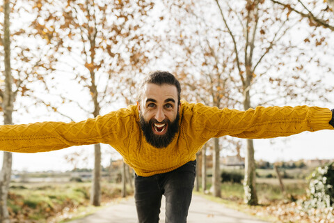 Junger Mann mit offenen Armen und glücklich in einem Park im Herbst, lizenzfreies Stockfoto