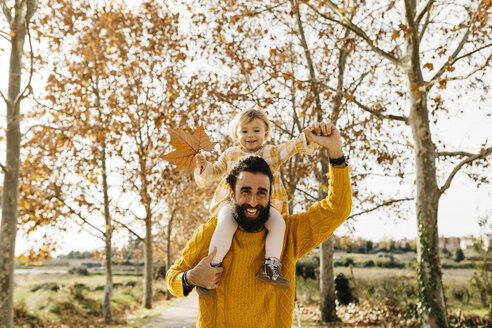 Vater trägt seine kleine Tochter auf den Schultern an einem Morgen im Park im Herbst - JRFF02268