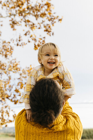 Vater hält seine Tochter an einem Morgen im Park im Herbst, lizenzfreies Stockfoto