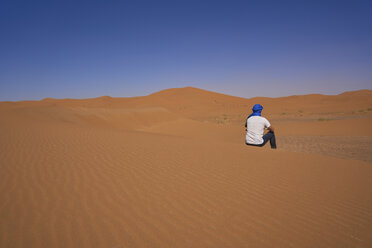 Morocco, back view of man sitting on desert dune - EPF00517