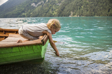 Little boy with fishing rod sitting on boat stock photo