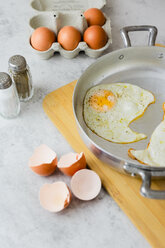 Eggs in a box, fried eggs in pan and eggshells - GIOF05289