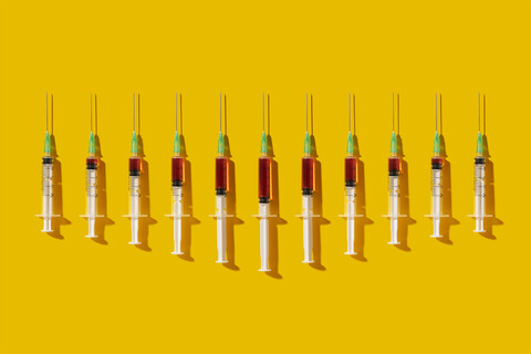 Multiple syringes organized in a pattern over yellow background stock photo